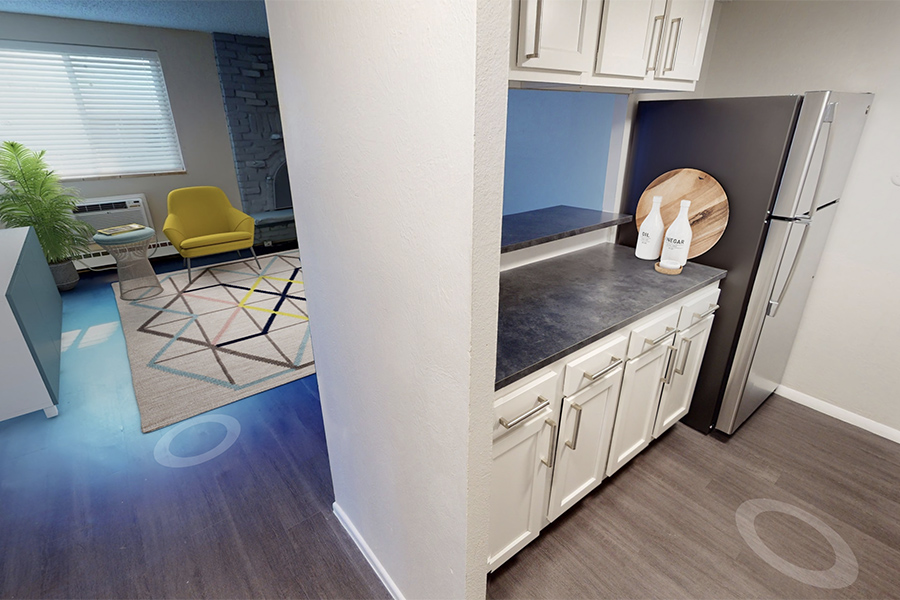 3D tour thumbnail showing kitchen and living area with wood floors and large rug.