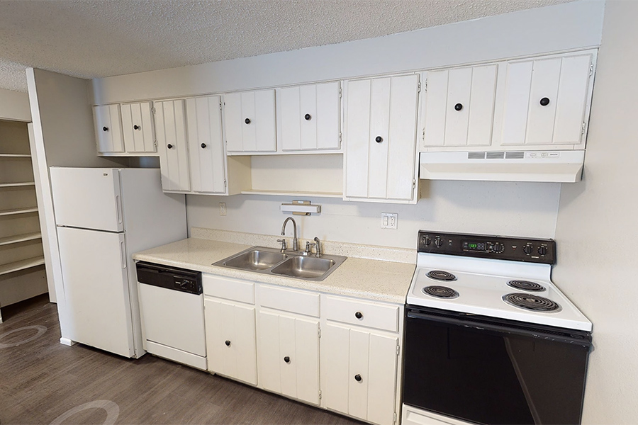 3D tour thumbnail showing kitchen area with wood floor and white cabinets and appliances.