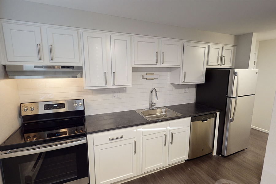 3D tour thumbnail showing kitchen area with wood floors, white cabinets, and dark counter.