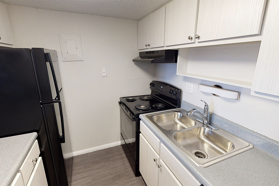 3D tour thumbnail showing kitchen with wood floor, white cabinets, and black appliances.