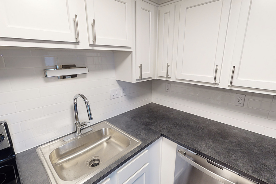 3D tour thumbnail showing dark kitchen counters with white cabinets and stainless sink.