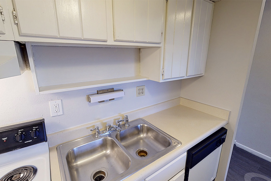 3D tour thumbnail showing kitchen with stainless steel double sink under large shelf and cabinets.