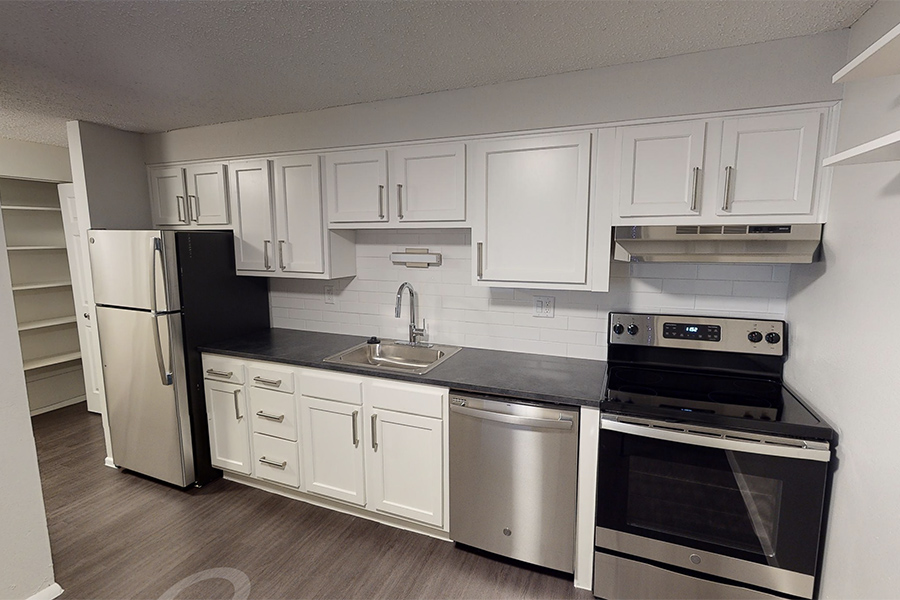 3D tour thumbnail showing kitchen with wood floors, white cabinets and stainless appliances.