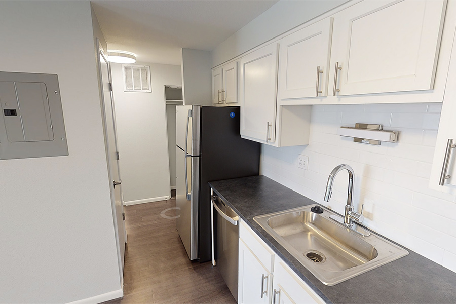 3D tour thumbnail showing kitchen with white cabinets, dark counters, and stainless sink and appliances.