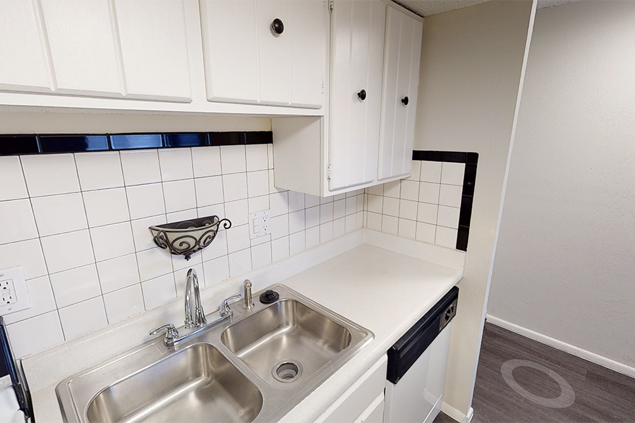 3D tour thumbnail showing detail of kitchen with double stainless sink, white cabinets, and tile backsplash.