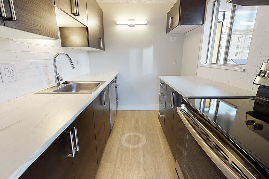 3D tour thumbnail for 1280 Lafayette showing kitchen with wood floor, dark cabinets, light counters, and stainless sink.