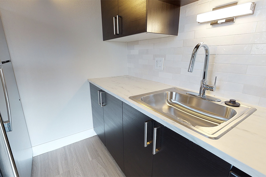 3D tour thumbnail for 1280 Lafayette showing kitchen with wood floor, dark cabinets, light counters, and tile backsplash.