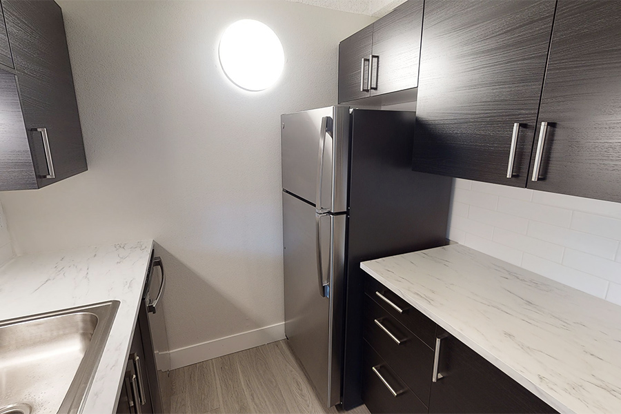 3D tour thumbnail for 1280 Lafayette showing kitchen with wood floor, dark cabinets, light counters, and soft dome light on wall.