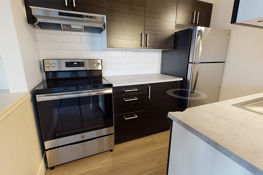 3D tour thumbnail for 1280 Lafayette showing kitchen with wood floor, dark cabinets, light counters, and stainless steel appliances.